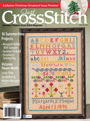 Cover of 'Just CrossStitch' magazine featuring a cross-stitched design with alphabets and numbers.
