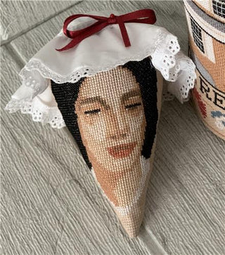 Decorative item shaped like a cone with a face and bow, next to a cylindrical container.
