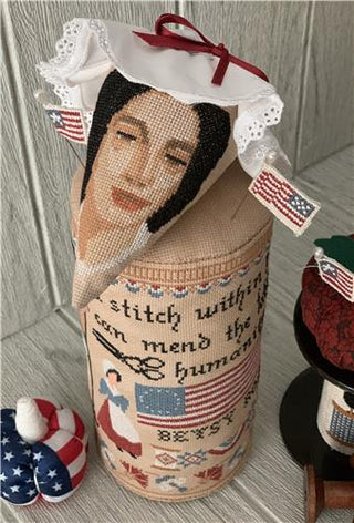 Decorative bottle with embroidered face and text, surrounded by small American flag-themed items.