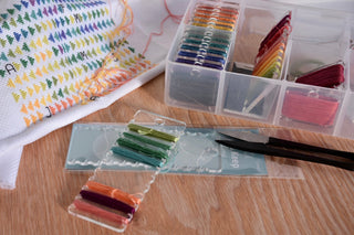 Set of colorful thread spools in a clear plastic case on a wooden surface.