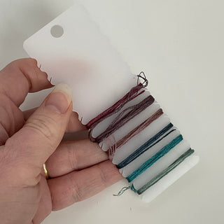 Color swatch with multicolored threads held by a hand against a white background