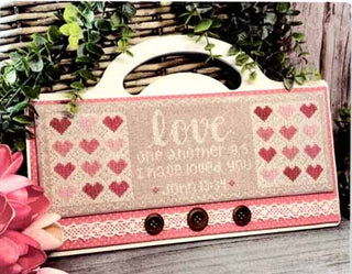 Cross stitch design with heart patterns and the word 'love' on a rustic background.