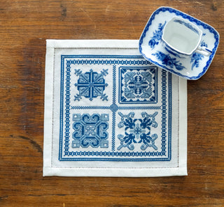 Decorative blue and white patterned cloth on a wooden surface with a small dish.