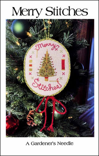 Cross-stitched Christmas ornament featuring a decorated tree, red “Merry Stitches” text around the circle, colorful buttons, and spool motifs, displayed hanging on a pine branch.