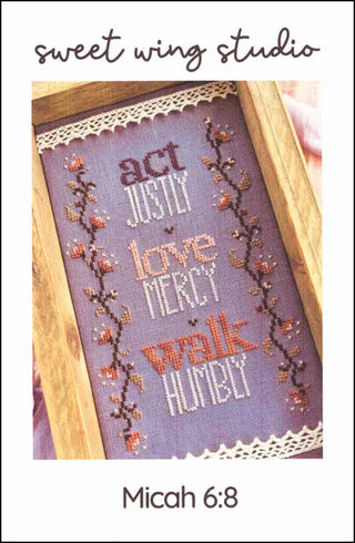 Micah 6:8 cross stitch pattern by Sweet Wing Studio featuring the verse “Act justly, love mercy, walk humbly” with floral borders on dark fabric.