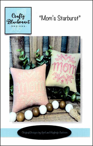 Two embroidered pillows with 'Mom' and 'Home Sweet Home' text on a wooden background with decorative elements.