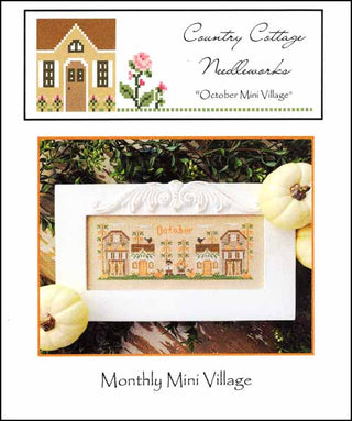 Promotional image for Country Cottage Needleworks' 'October Mini Village' with a cross-stitch design and pumpkins.