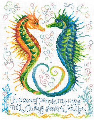 Cross-stitched design of two seahorses intertwined with hearts and text on a white background.