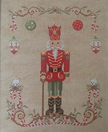 Cross stitch design featuring a red and green nutcracker surrounded by ornaments, greenery, and a decorative holiday border on a beige background.