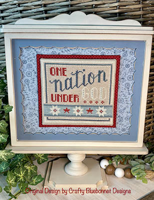 Decorative cross-stitch design with 'One Nation Under God' text on a white frame.