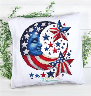 Decorative pillow with American flag cross stitch design featuring stars and stripes, displayed on a white background.