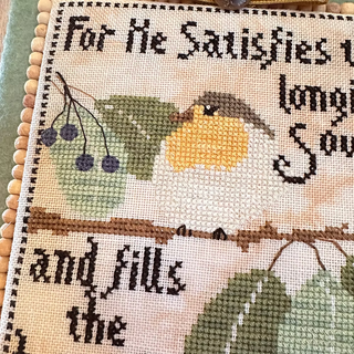 Cross-stitched piece with a bird and text on fabric