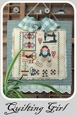 Quilt with 'Quilting Girl' design on a wooden shelf with sewing-themed elements.