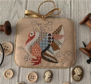 Decorative cross stitch ornament with a turkey design on a wooden surface with buttons.
