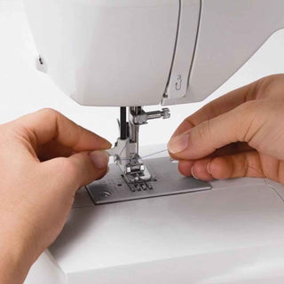 Person adjusting a sewing machine needle with close-up focus on hands and machine.