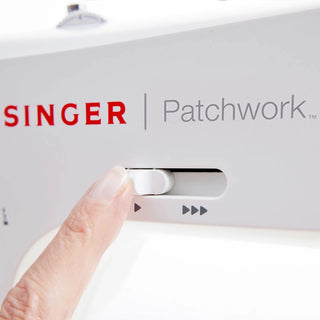 Singer Patchwork sewing machine with a hand pressing a button on the control panel.