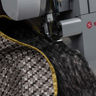 Serger machine stitching a piece of fabric with a finished edge.