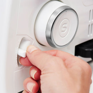 Hand pressing a button on a white electronic device with a brand logo.