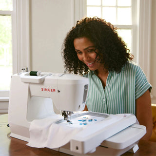 Woman using a Singer sewing machine in a bright room
