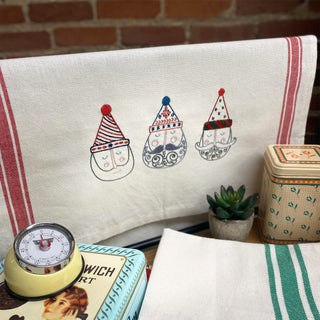 Decorative towel with gnome illustrations on a table with a clock and plant.