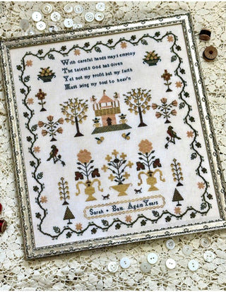 Decorative sampler with intricate patterns and text on a lace background