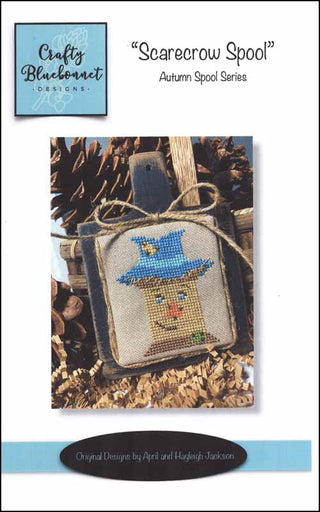 Scarecrow-themed cross-stitch pattern with blue border and text about Crafty Bluebonnet Designs.