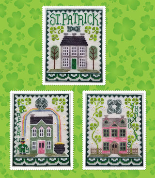 Three cross-stitched designs of houses on a green background with shamrocks.