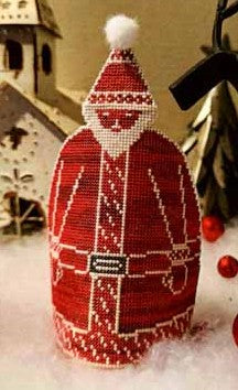 Decorative Santa figure with red coat and white hat, standing in a snowy landscape with a small house and trees in the background.