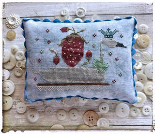 Small pillow finished cross-stitch of a crowned swan in a boat surrounded by red strawberries and tiny motifs, stitched on blue linen, designed by Lucy Beam.