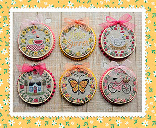 Six summer-themed circular cross stitch designs by Waxing Moon Designs showing butterflies, flowers, a bicycle, house, and “Hello Summer” design.