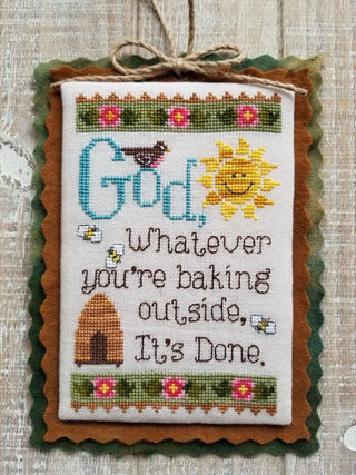 Cross-stitched sampler with a sun, birdhouse, and text on a textured background