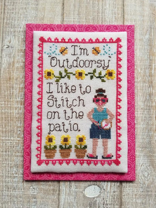 Cross-stitched patch with text and images of a person and sunflowers on a wooden background