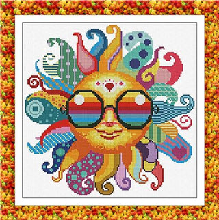 Cross stitch design of a smiling sun wearing rainbow sunglasses with swirling, colorful patterned rays in a retro psychedelic style by Alessandra Adelaide Needleworks.