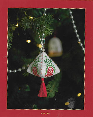 Decorative embroidered ornament with tassel hanging on a Christmas tree.