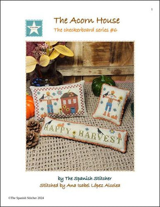 Three small cross-stitched pillows with scarecrows, pumpkins, sunflowers, and Happy Harvest text in warm fall colors on beige fabric.