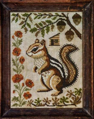 Cross stitch design featuring a realistic standing chipmunk surrounded by orange flowers, oak leaves, acorns, and a small birdhouse on a rustic autumn-themed background.
