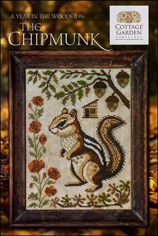 Cross stitch design featuring a realistic standing chipmunk surrounded by orange flowers, oak leaves, acorns, and a small birdhouse on a rustic autumn-themed background.