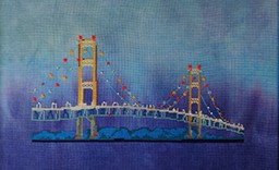 Cross stitch pattern of the Mackinac Bridge at dusk with soft watercolor-style fabric background in shades of blue and gray, designed by Meridian Designs.