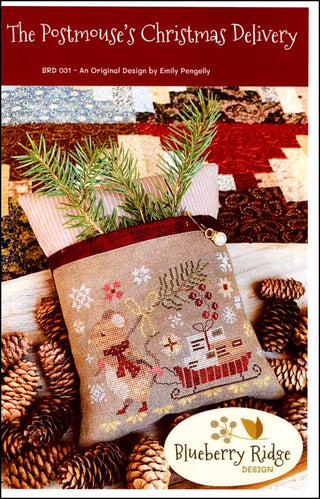 The Postmouse’s Christmas Delivery cross stitch pattern by Blueberry Ridge Designs featuring a festive mouse carrying holiday mail on a pillow design surrounded by pinecones and evergreen accents.