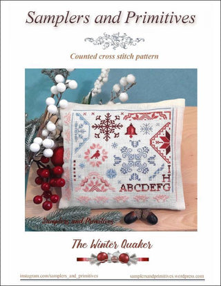 Cross stitch pattern for a pillow with winter-themed design on a wooden surface.
