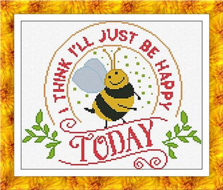 Cross-stitch design featuring a smiling bee with the phrase “I think I’ll just be happy today” in a circular layout with green accents.