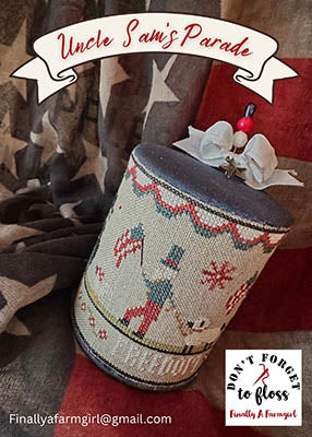 Patriotic cross stitch drum featuring a folk-style Uncle Sam with stars and red white and blue motifs in a vintage Americana design.