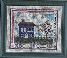 Cross stitch sampler with a blue cottage, tree, alphabet border, and cloudy sky on mottled fabric.