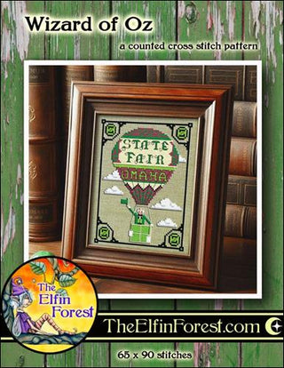 Framed cross-stitch pattern of a hot air balloon with 'State Fair' text, set against a green background with books.