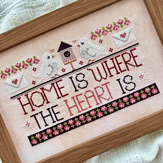 Cross-stitched embroidery with 'Home is where the heart is' text and birdhouses.