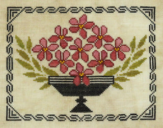 Cross-stitched design of pink flowers in a black vase on beige fabric.